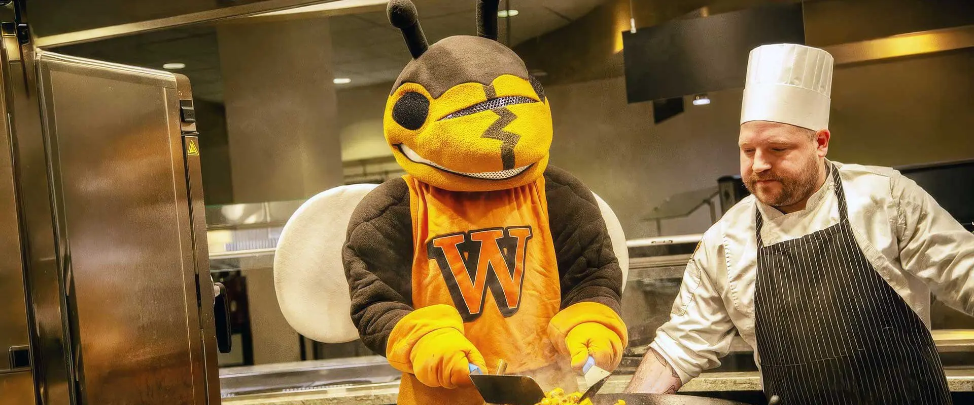 Mascot cooking hibachi while chef looks on