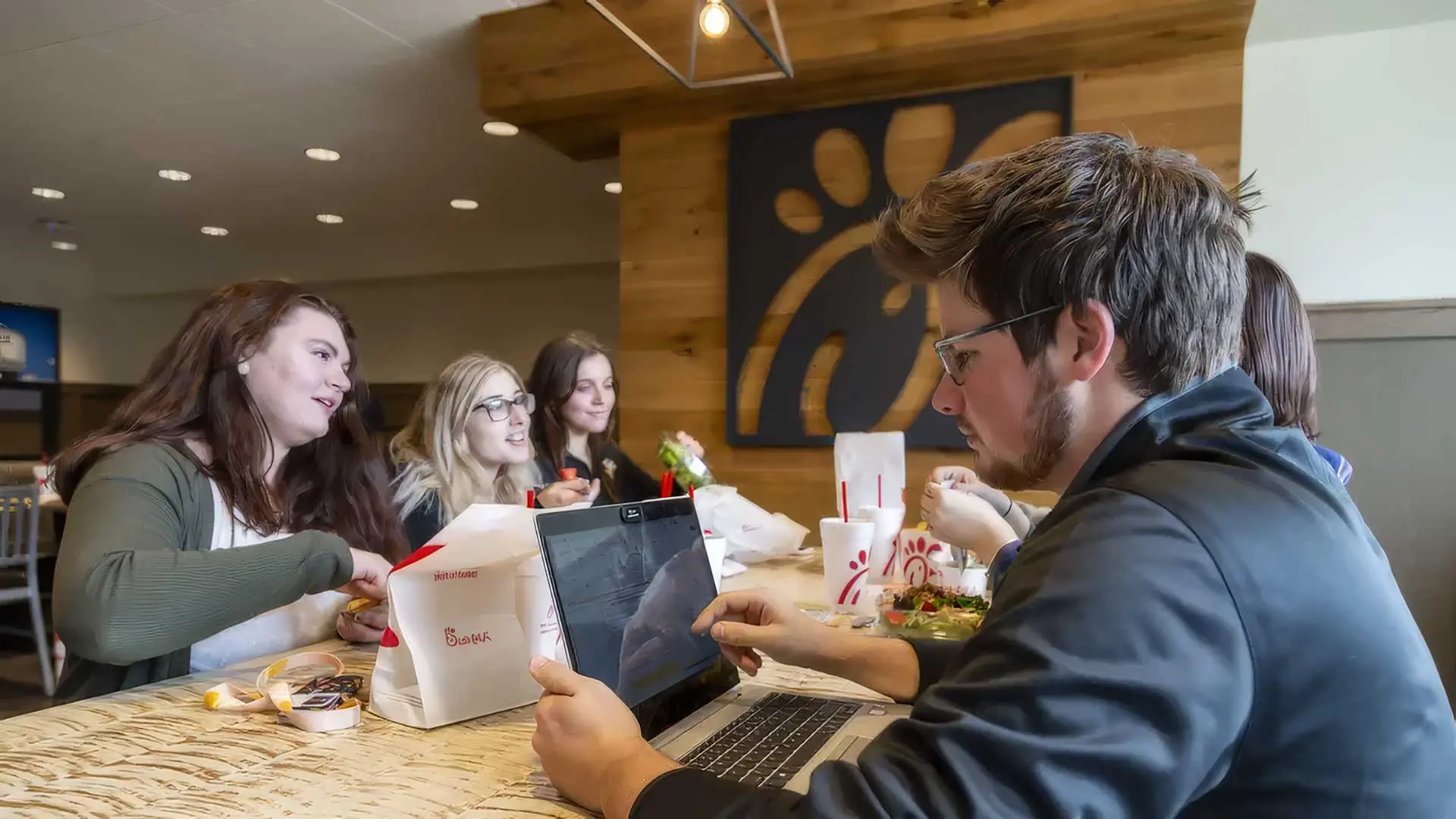 Students having a meal at Chick-fil-A while another works on laptop