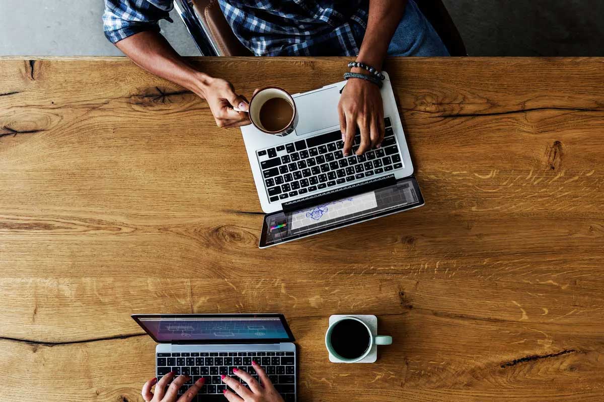 Overhead shot of people working on laptops and drinking coffee