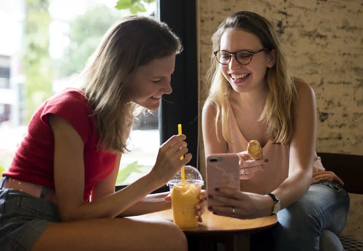 Two students enjoying a treat while looking at phone